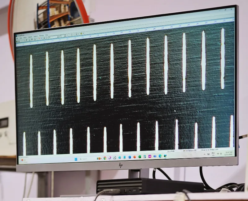 High-magnification image of laser-cut filtration slots displayed on a monitor during digital quality inspection.