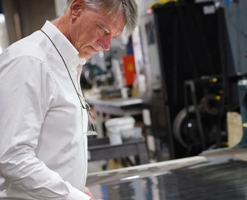 Senior technician closely inspecting a large metal filtration sheet on the factory floor.