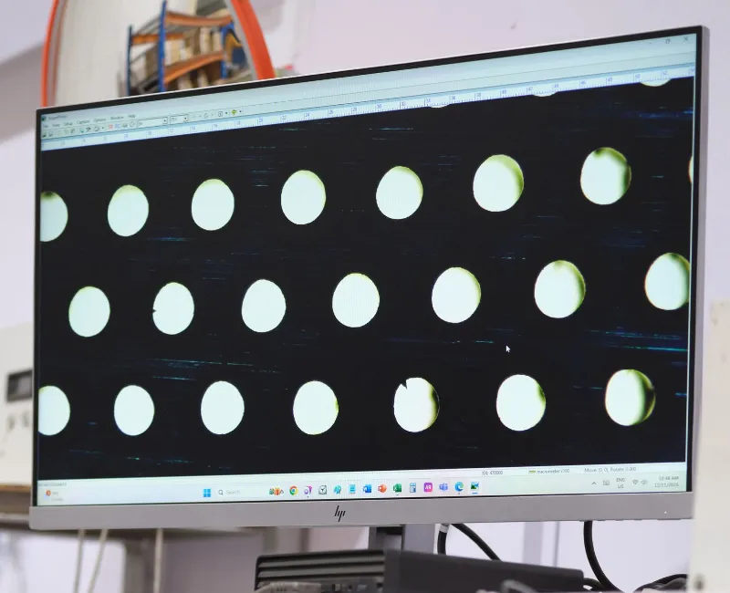 High-magnification image of circular laser-cut holes displayed on a monitor during quality inspection.