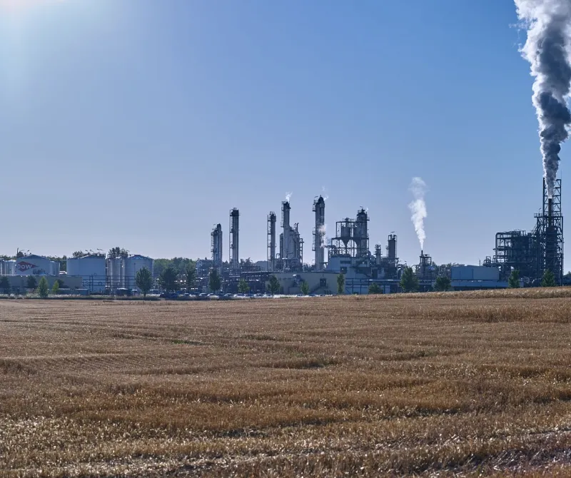 over a mowed field to the modern chemical plant